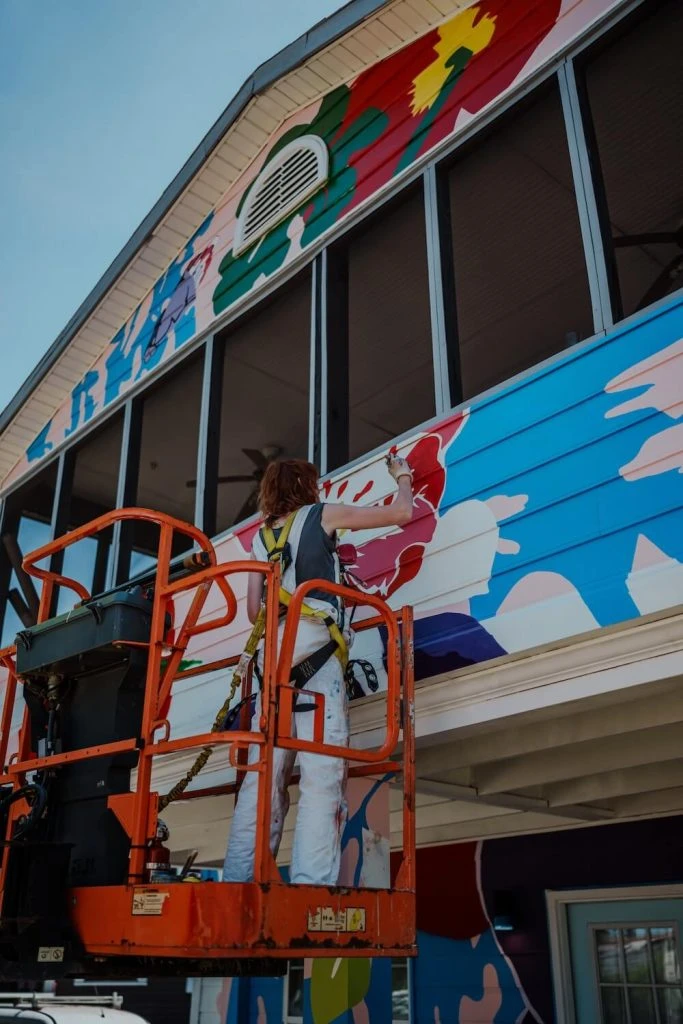 view of artist on lift painting building plaza midwood charlotte