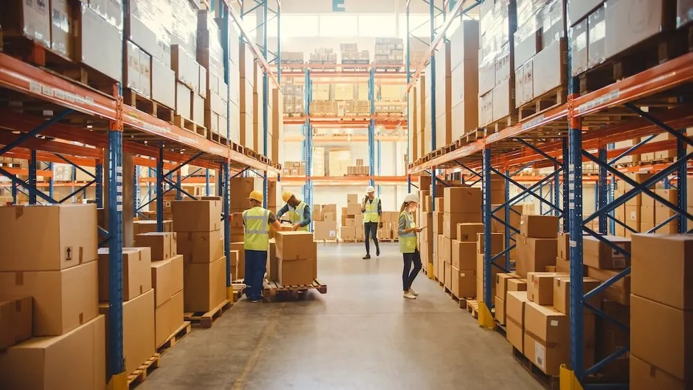 warehouse workers in large warehouse lined with shelves